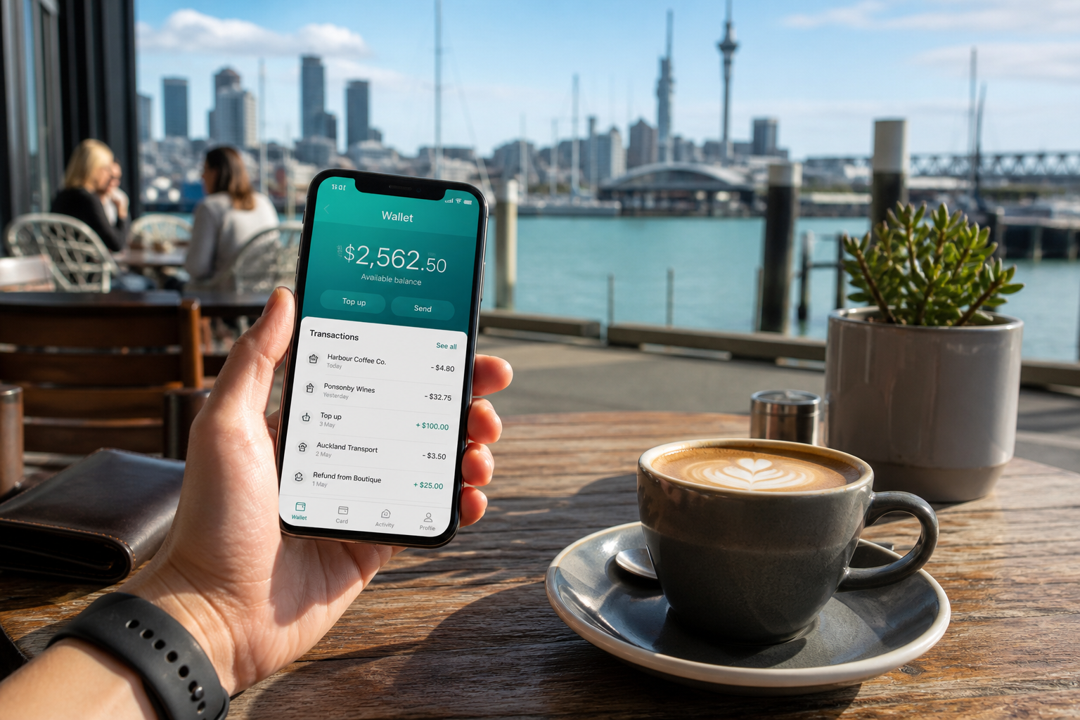 Sunny Auckland cafe with a phone showing an original digital wallet balance and recent payments