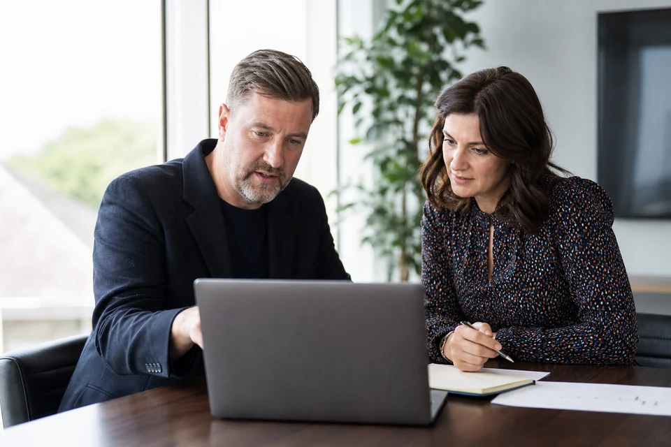 UK business owner and AI consultant reviewing an AI project budget and timeline on a laptop