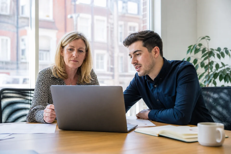 UK business owner and web consultant reviewing website cost and growth plans on a laptop