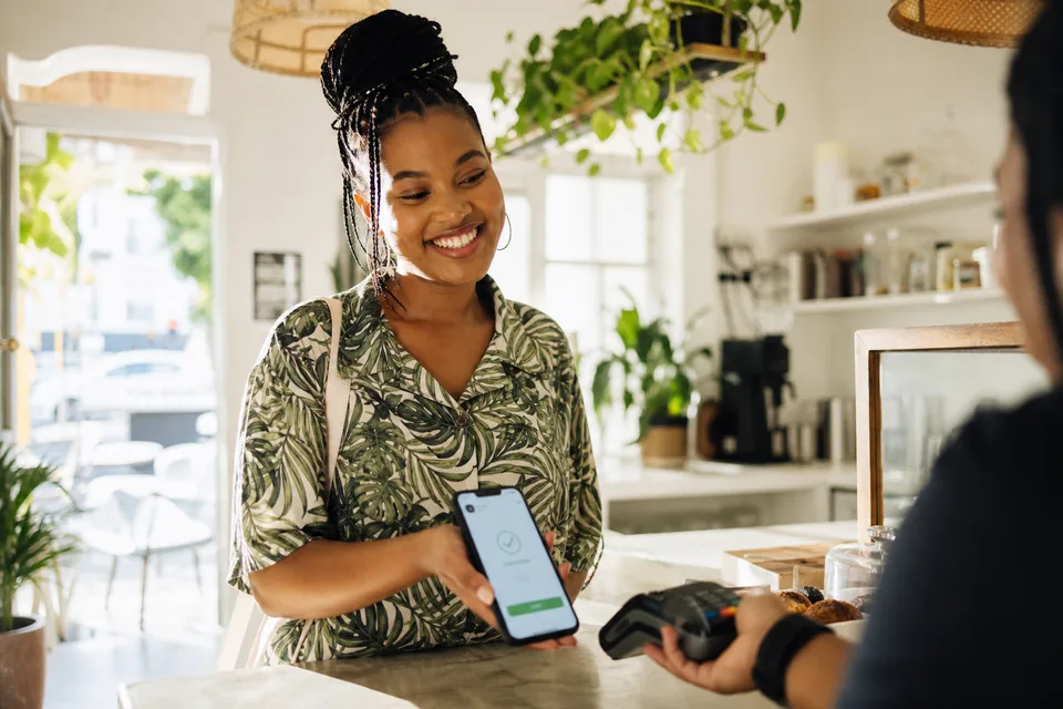 South African user completing a digital wallet payment on a bright cafe terrace
