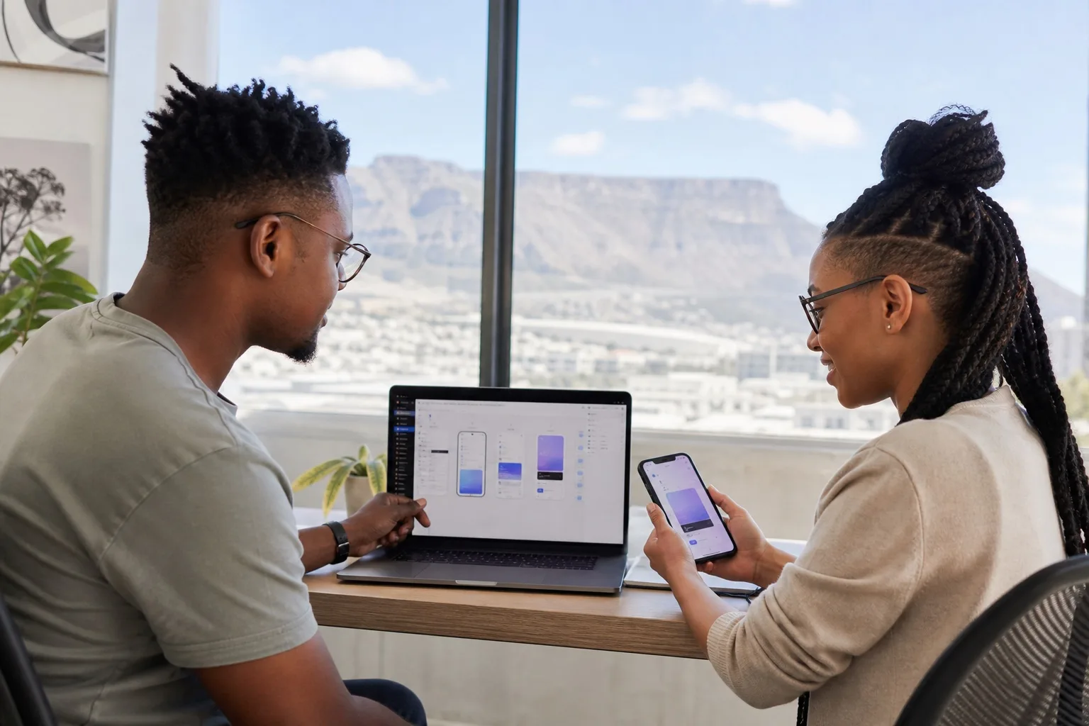 South African iOS developers reviewing SwiftUI screens on a MacBook and iPhone in a bright Cape Town studio